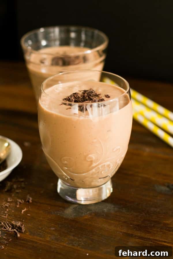 Two glasses of luscious chocolate peanut butter smoothie with chocolate garnish on top, showcasing its rich, creamy texture.