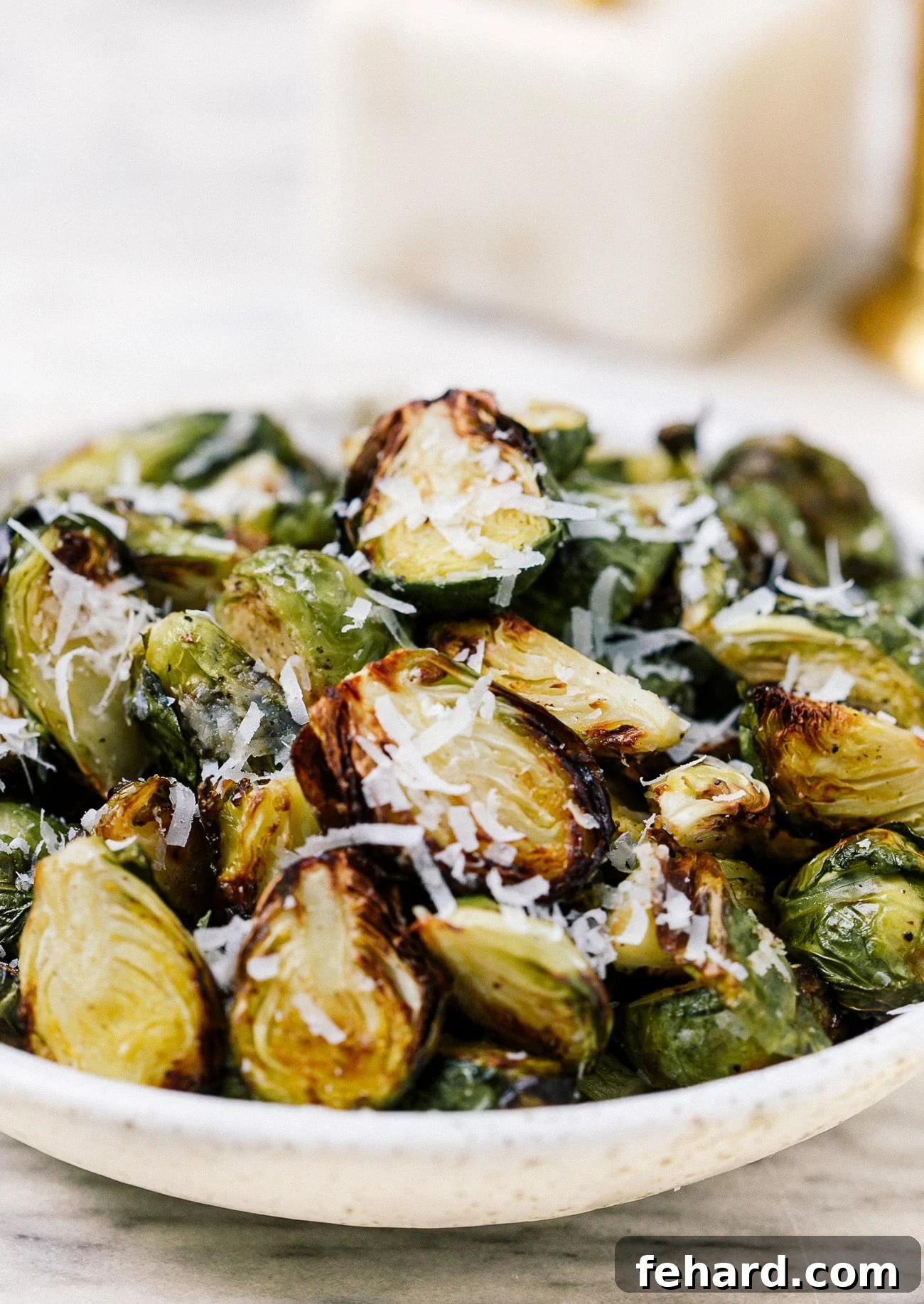 A serving bowl full of air fryer Brussels sprouts topped with parmesan cheese. 