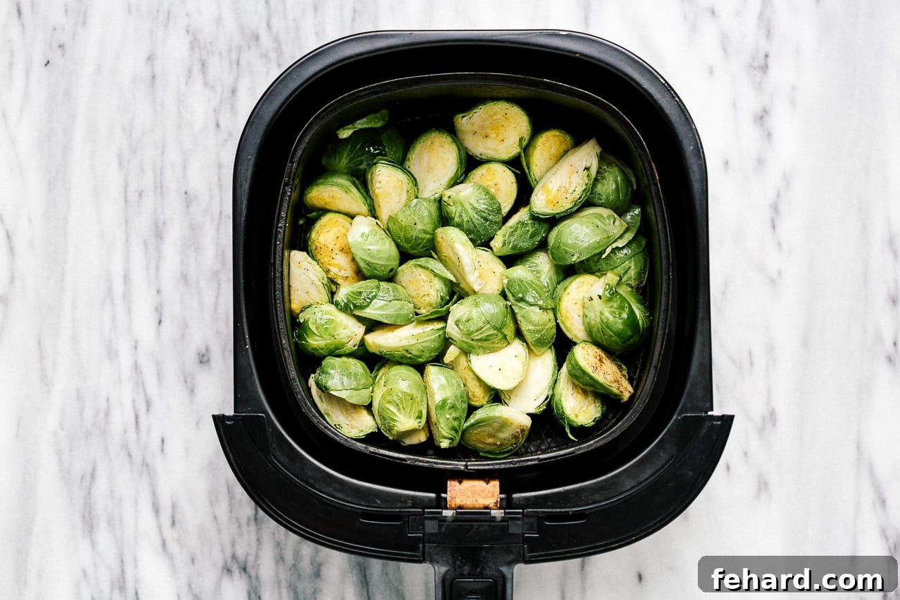 Seasoned Brussels sprouts in the air fryer basket.