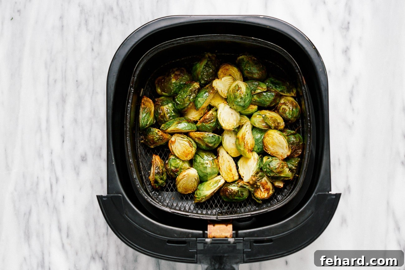 Cooked Brussels sprouts in a black air fryer basket.