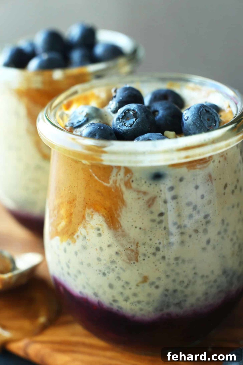 A delightful glass serving cup filled with beautifully swirled peanut butter and jelly chia pudding, elegantly topped with plump, fresh blueberries.
