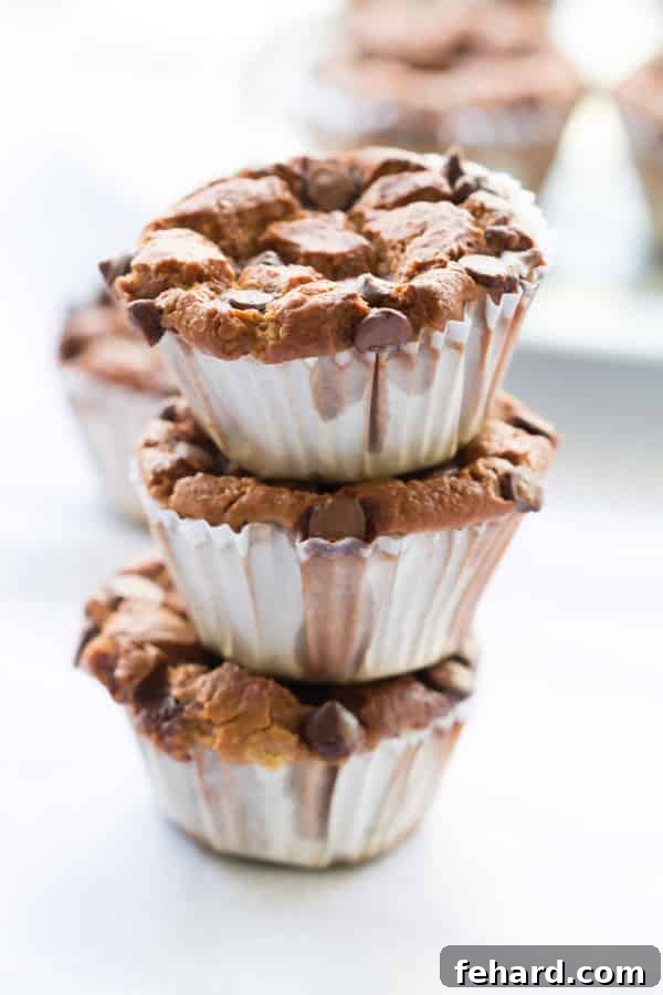 One-Bowl Blender Banana Oatmeal Muffins 4 Blender Banana Oatmeal Muffins stacked in a pyramid on a white plate, showcasing their inviting texture.