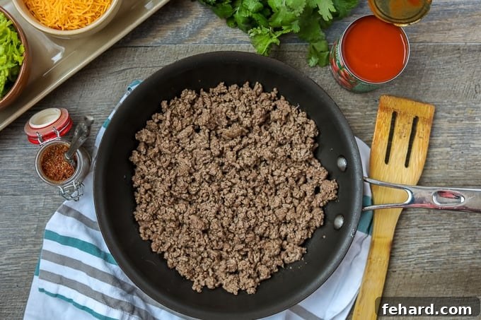 Ground beef beautifully browned and crumbled in a skillet, ready for seasoning.