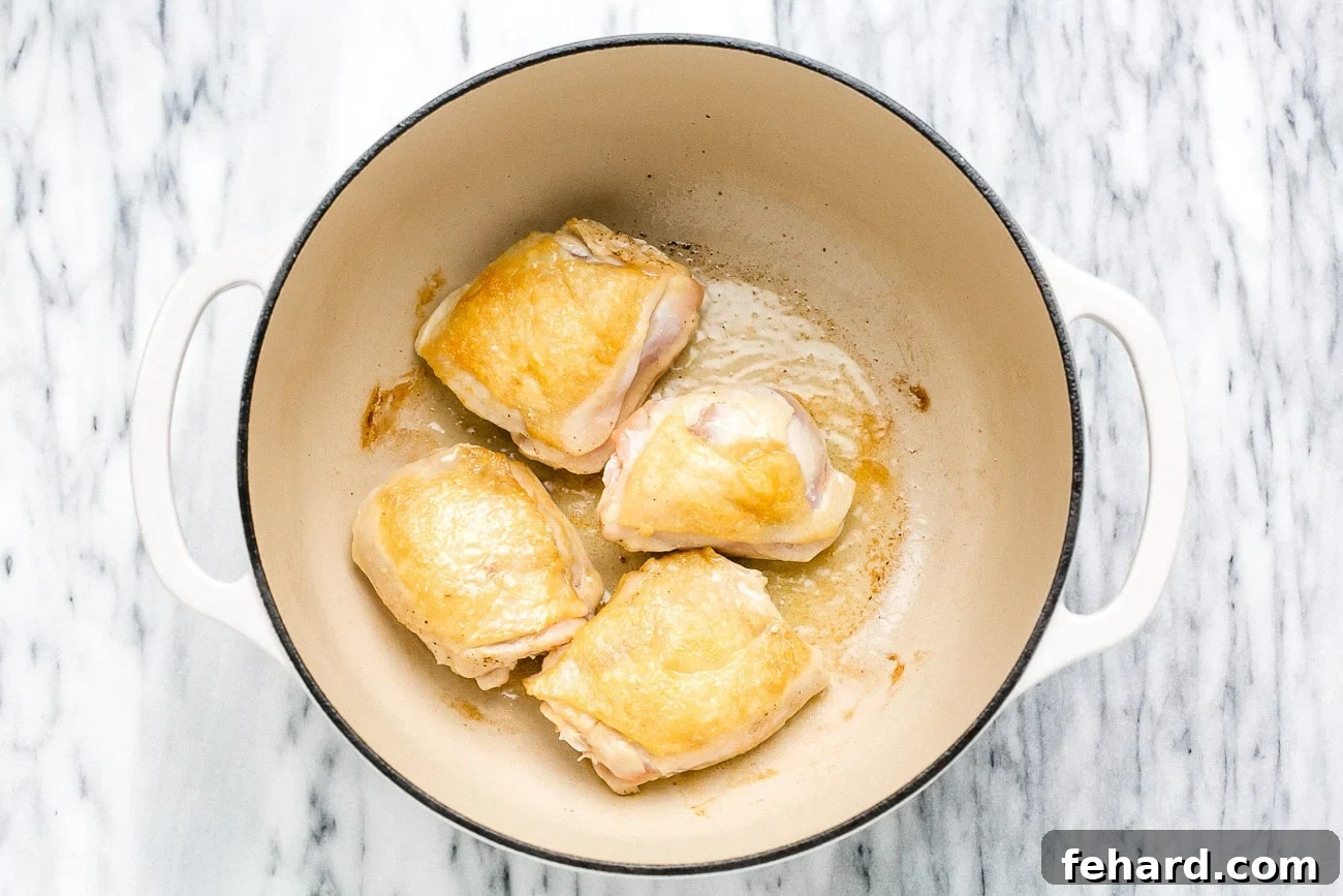Searing chicken thighs in oil.