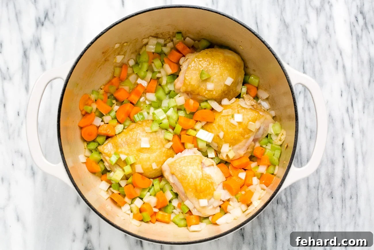Diced onion, carrots and celery added to seared chicken thighs. 