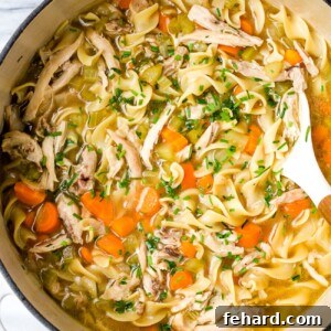 Chicken noodle soup in a large white pot.