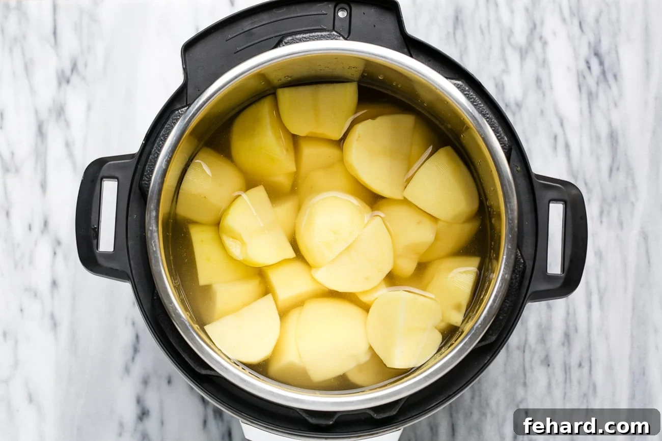 Peeled and quartered potatoes covered in water in an instant pot, ready for pressure cooking.