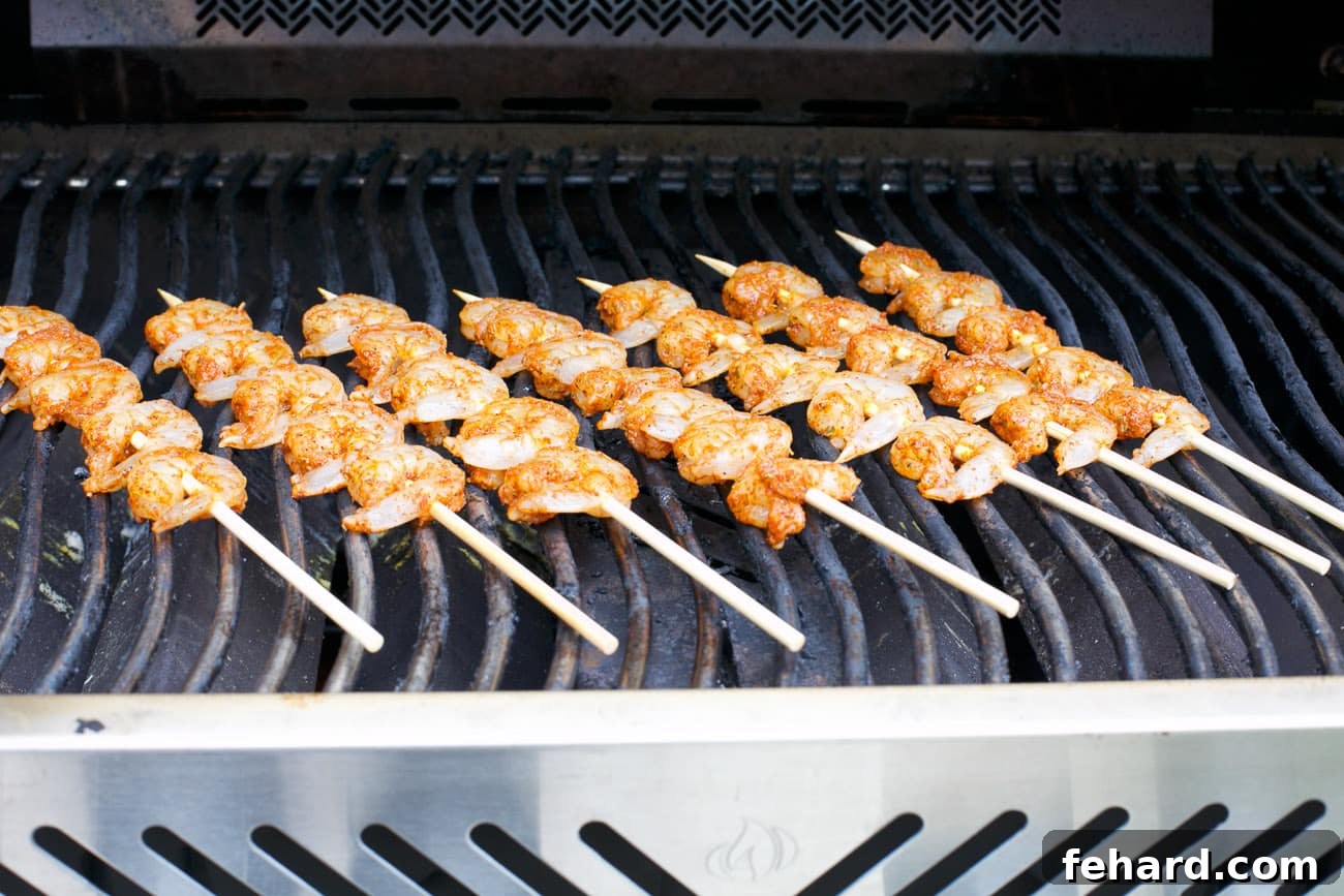 Cajun shrimp skewers cooking on a hot grill, showing grill marks.