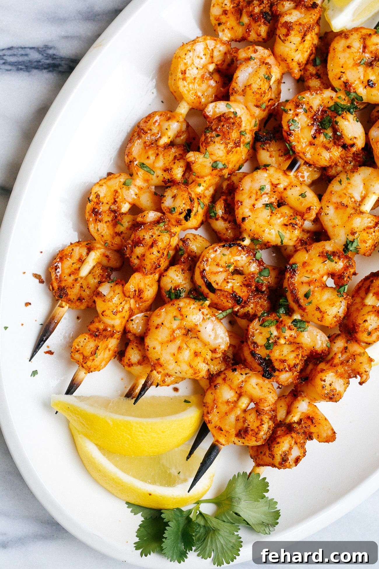 close-up view of a perfectly grilled cajun shrimp skewer on a white plate, garnished with fresh herbs