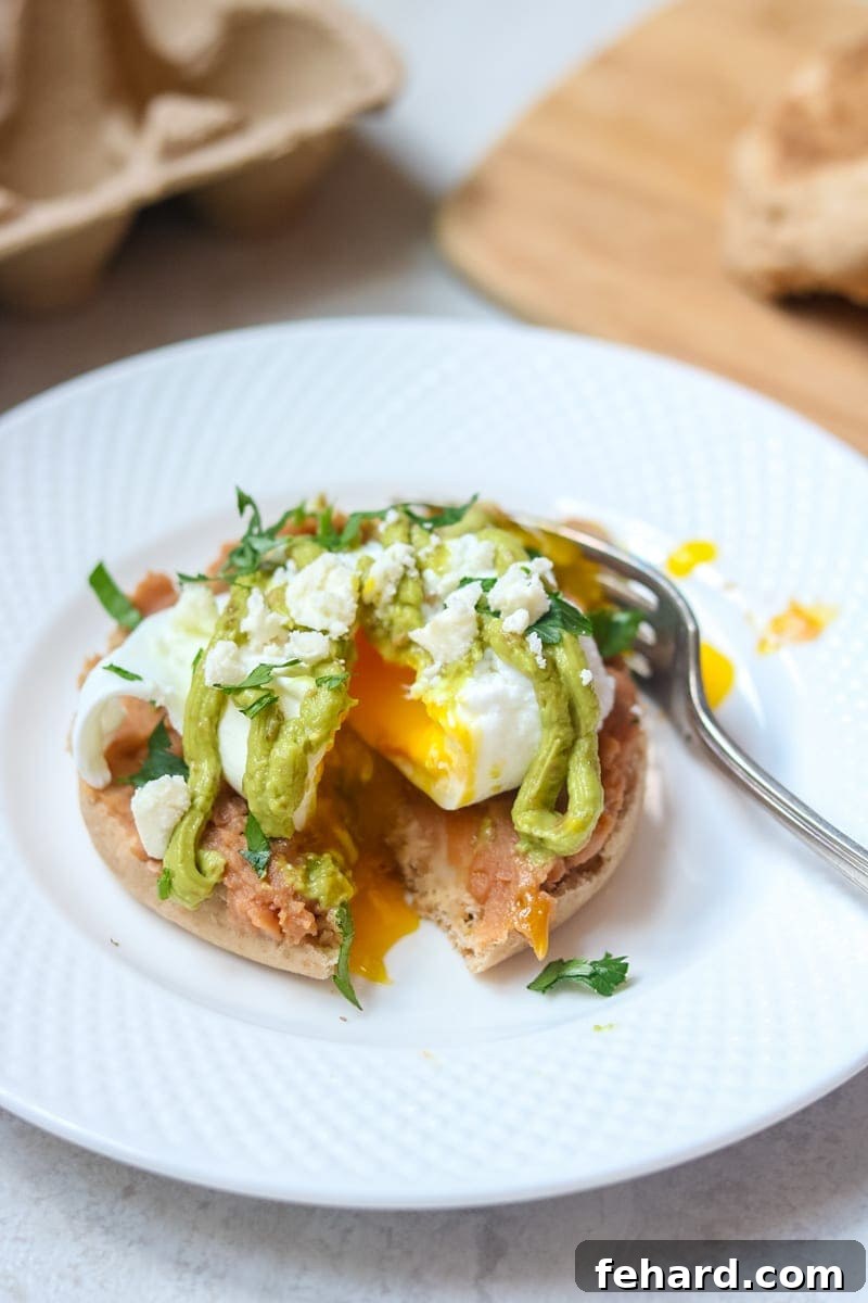 Zesty Tex Mex Benedict Featuring Avocado Hollandaise 2 Poached egg on top of english muffin cut open with yolk running out, drizzled with avocado hollandaise