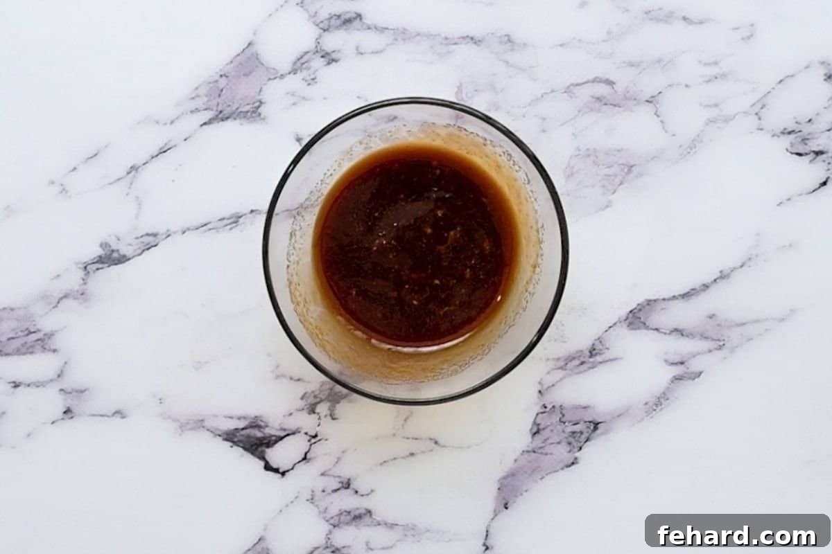 Homemade Tonkatsu Sauce ingredients being mixed in a bowl, showcasing its rich, dark color.