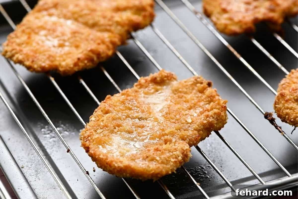 Golden brown, crispy breaded chicken cutlets fresh out of the oven, resting on a baking rack.