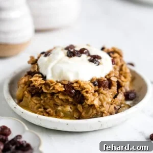 A delicious slice of Baked Oatmeal with Apples and Raisins topped with a swirl of yogurt and a drizzle of syrup, ready to be served.