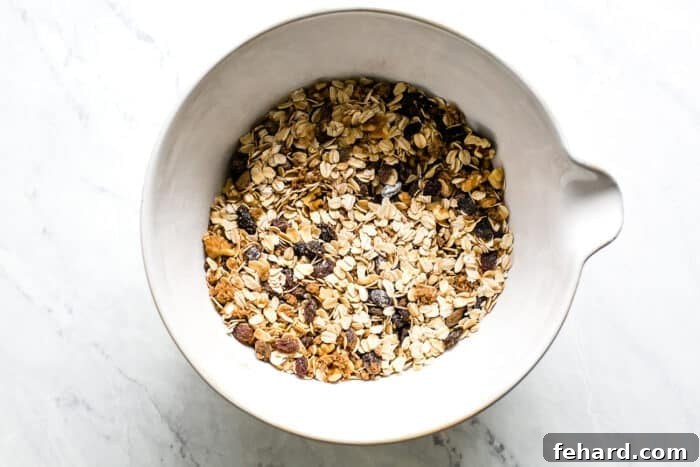 Comforting Apple Raisin Oatmeal Bake 5 The dry ingredients for baked oatmeal – oats, brown sugar, cinnamon, baking powder, salt, walnuts, and raisins – are perfectly mixed in a large bowl, ensuring even distribution of flavors.