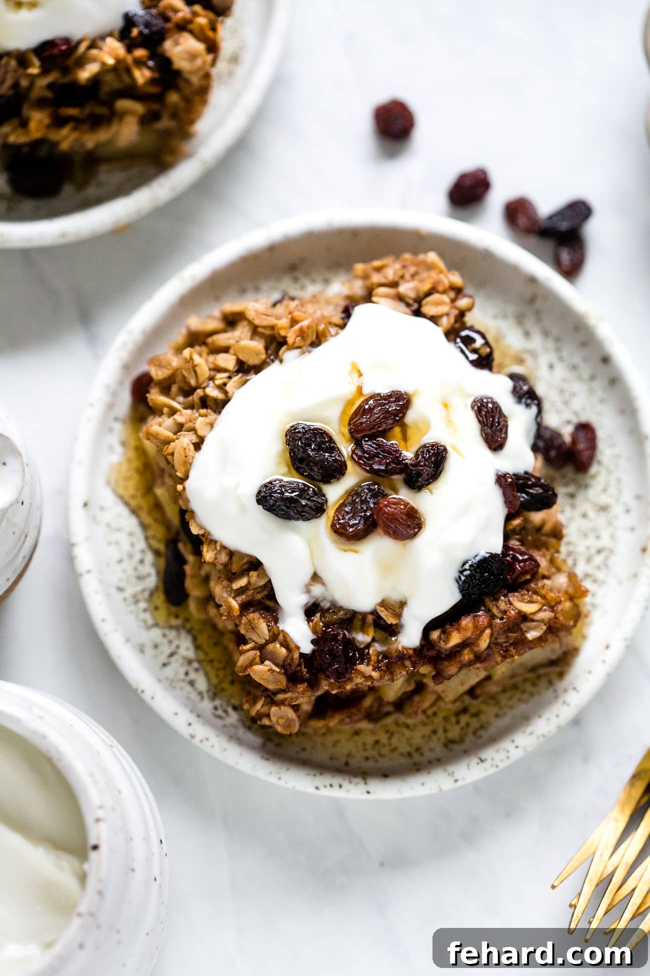 Comforting Apple Raisin Oatmeal Bake 10 A beautifully plated slice of Apple & Raisin Baked Oatmeal, garnished with a generous dollop of creamy Greek yogurt and a drizzle of rich maple syrup, ready to be enjoyed.