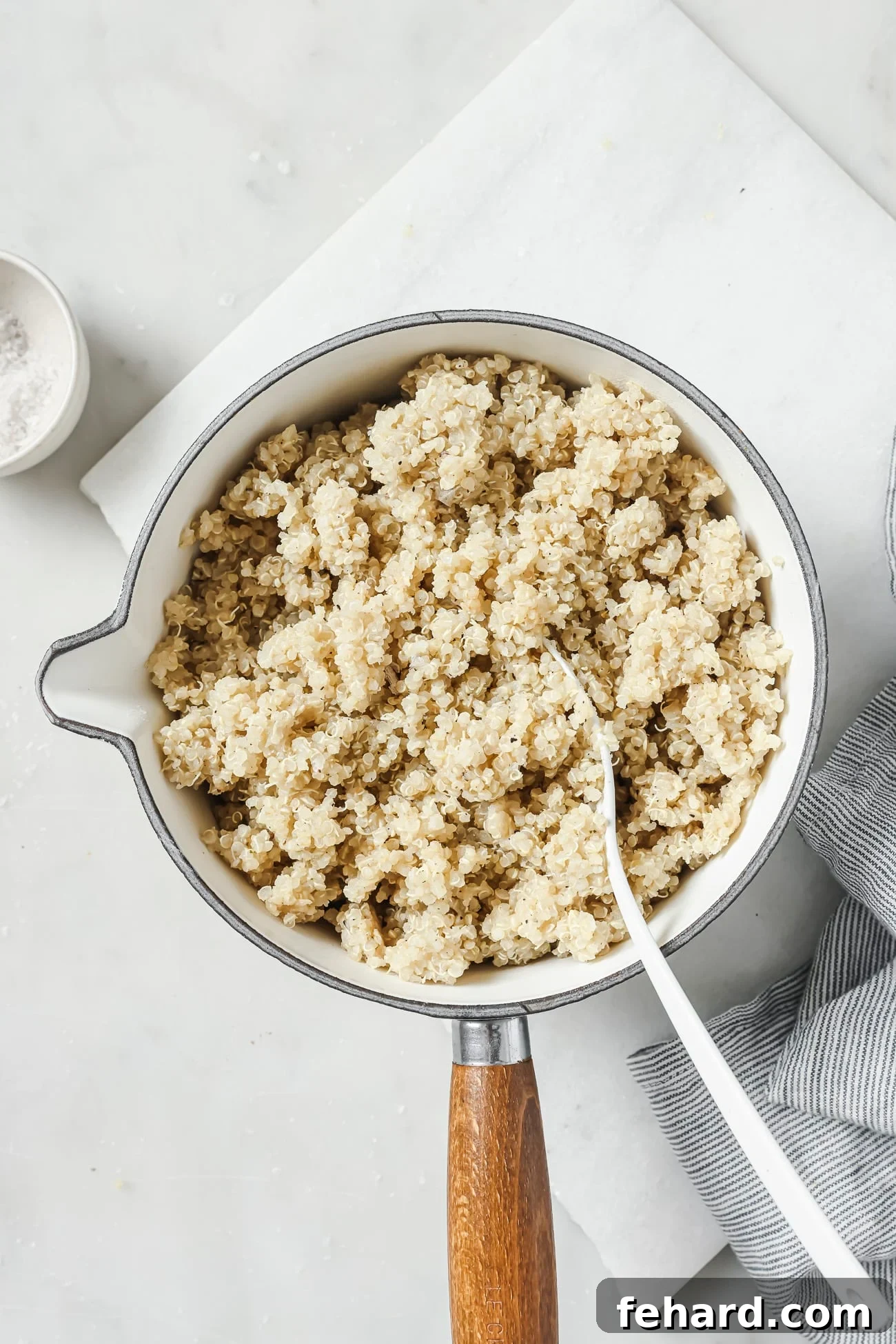 Close-up of perfectly cooked, fluffy quinoa in a ceramic pot, with steam gently rising, showcasing its light and separated grains.