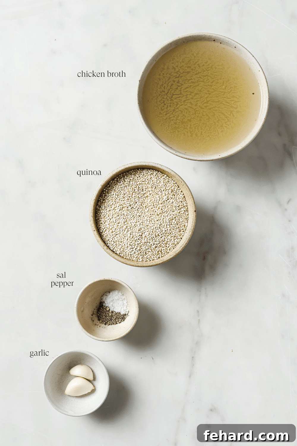 Pre-measured ingredients for cooking fluffy quinoa, neatly arranged in small white bowls: dry quinoa, clear broth, whole garlic cloves, and a pinch of salt and pepper.
