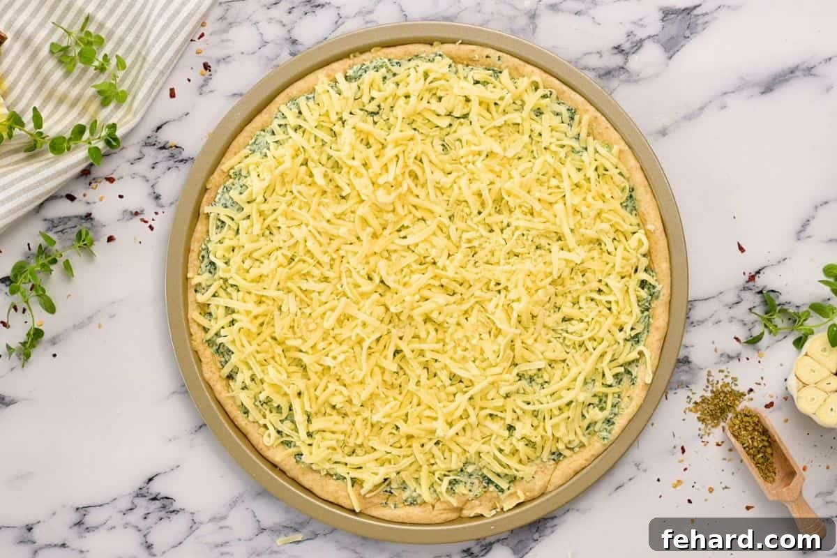 Florentine Pizza Recipe Pizza Crust with spinach, ricotta, and mozzarella cheese, ready for baking.
