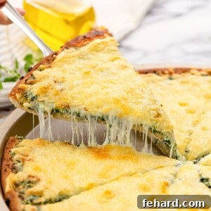 Slice of spinach pizza being pulled out from pizza tray.
