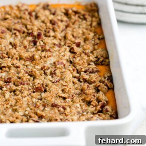 Close-up of a slice of baked sweet potato casserole with a golden brown pecan streusel topping, highlighting its delicious texture.