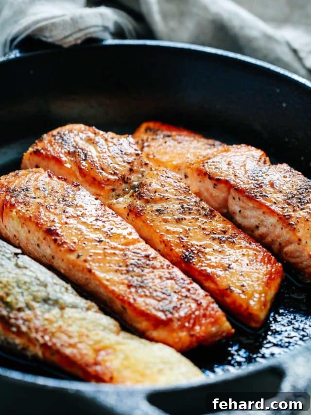 Any Night Salmon Dinner Recipes Baked Pan Seared or Broiled 15 A close-up shot of four perfectly pan-seared salmon fillets in a cast-iron skillet.