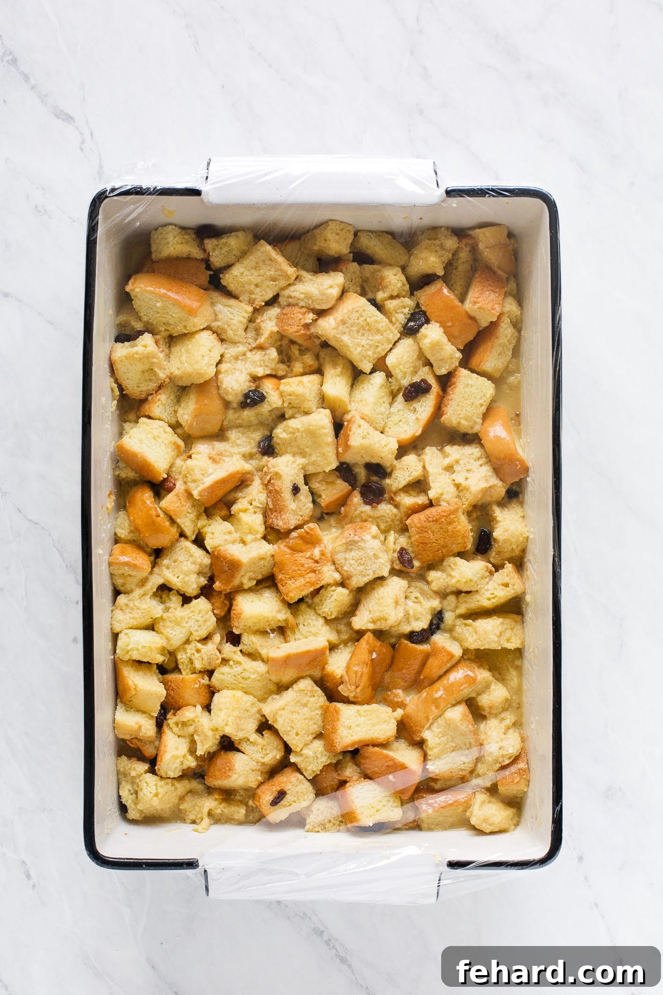 An assembled French toast casserole, tightly covered with plastic wrap and placed in the refrigerator to soak overnight.