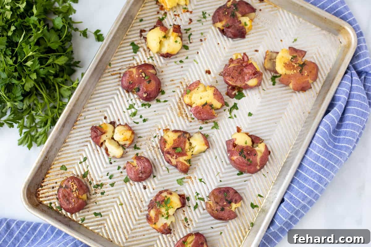 Golden brown garlic butter smashed potatoes on a sheet pan, fresh out of the oven.