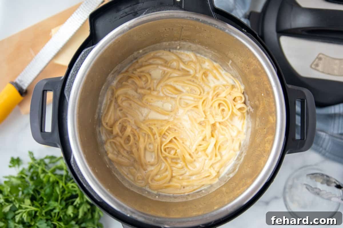 Cooked Instant Pot Fettuccine Alfredo Cooked fettuccine noodles in a creamy sauce inside the Instant Pot, ready for the final touches.