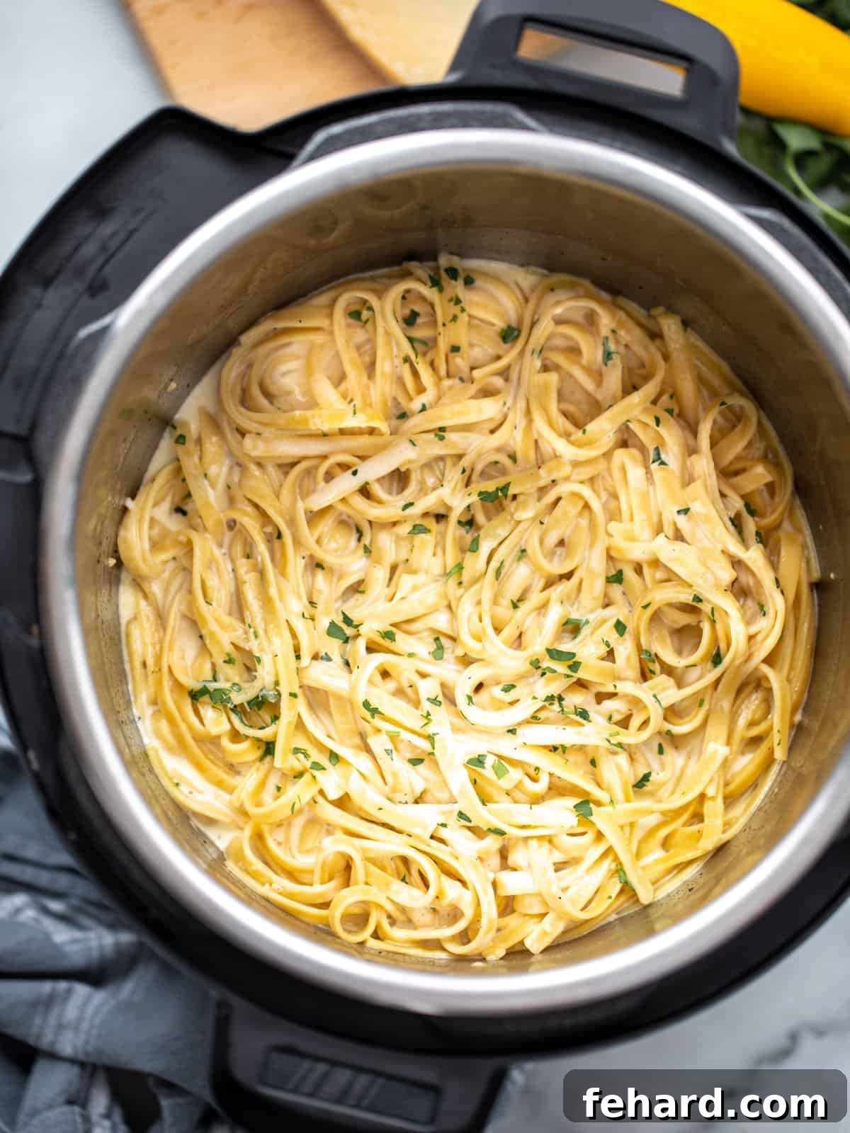 Fettuccine Alfredo Instant Pot Ready to Serve A large serving of cooked Fettuccine Alfredo in an electric pressure cooker, garnished with herbs, ready to be served.