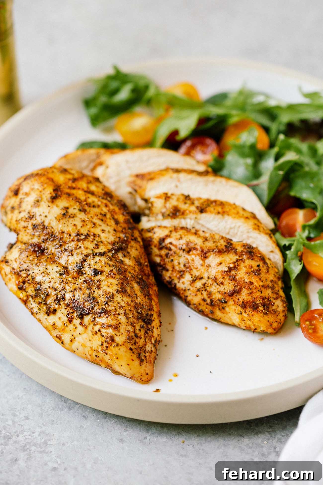 Flavorful Gluten-Free Dinners 4 A close-up of two perfectly cooked air fryer chicken breasts on a white plate, showcasing a crispy exterior.