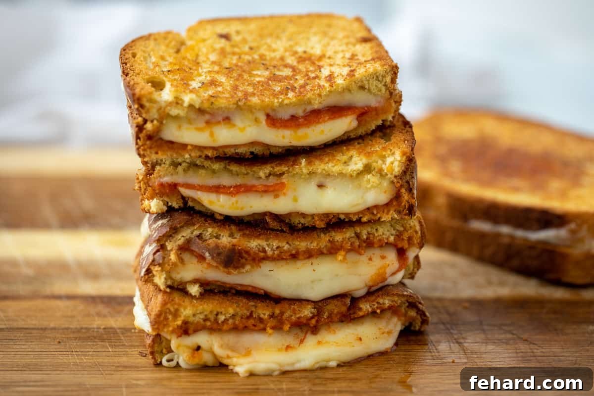 Easy Pizza Grilled Cheese Sliced pizza grilled cheese sandwiches on cutting board.