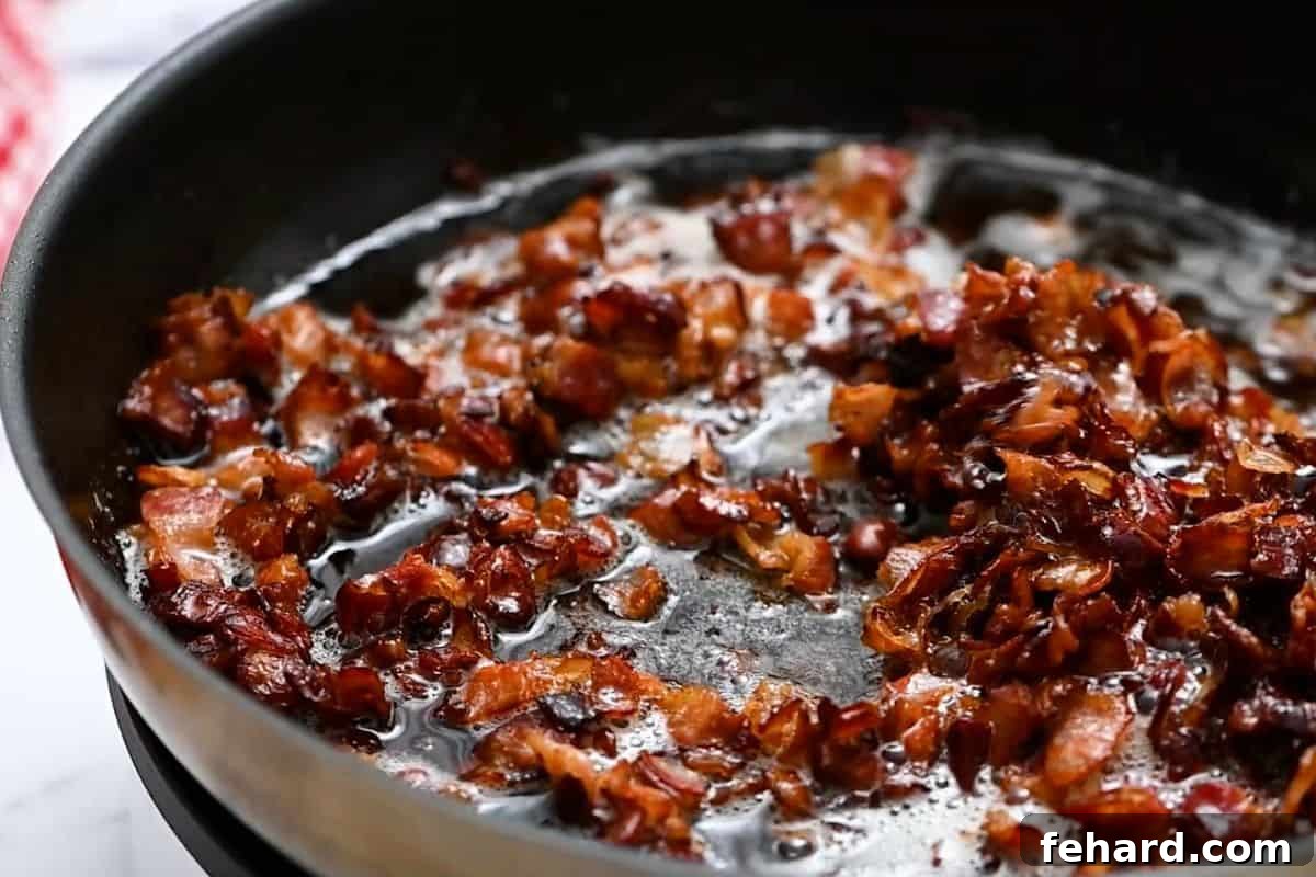 Crispy Bacon for Pasta Salad Close-up of diced bacon pieces, perfectly browned and crispy, in a large skillet after cooking.