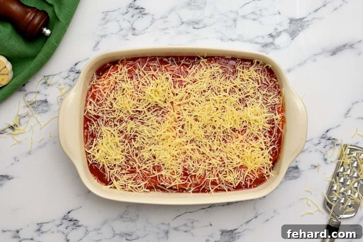 The layered chicken enchilada casserole in a baking dish, perfectly assembled and ready for the oven.