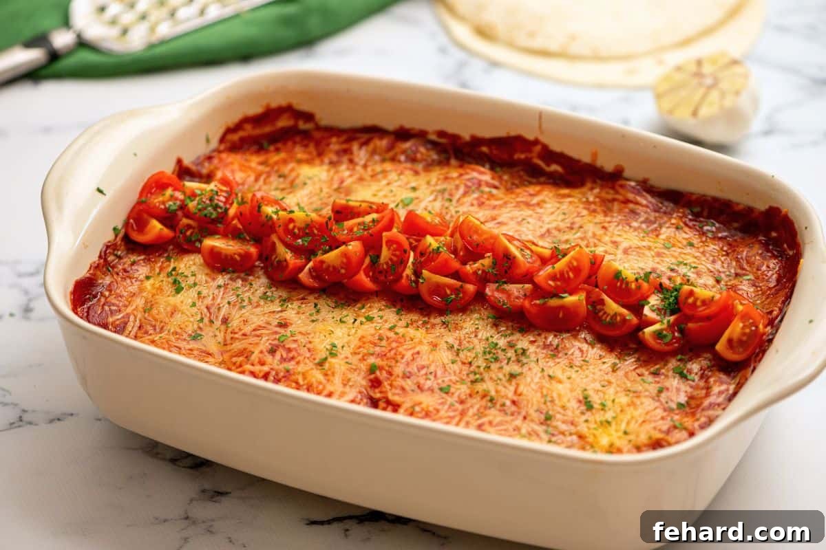 A freshly baked Chicken Enchilada Casserole in a baking dish, garnished with vibrant minced cilantro and diced tomatoes.