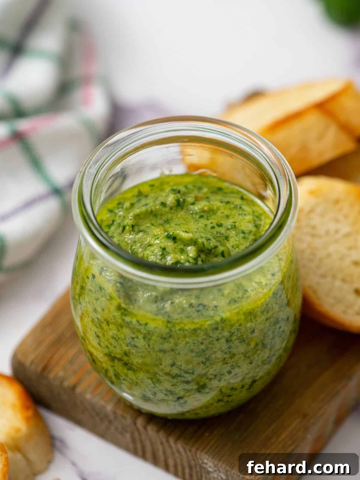 Jar of prepared basil pesto next to toasted bread, highlighting fresh ingredients.