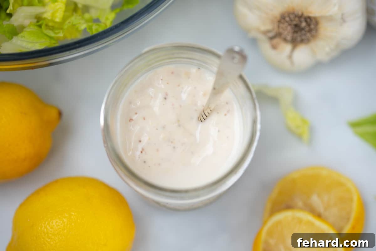 Caesar Dressing Recipe without Raw Eggs Jar of homemade caesar dressing next to fresh lemons.
