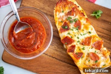 French Bread pizza with pepperoni on wooden cutting board next to pizza sauce.