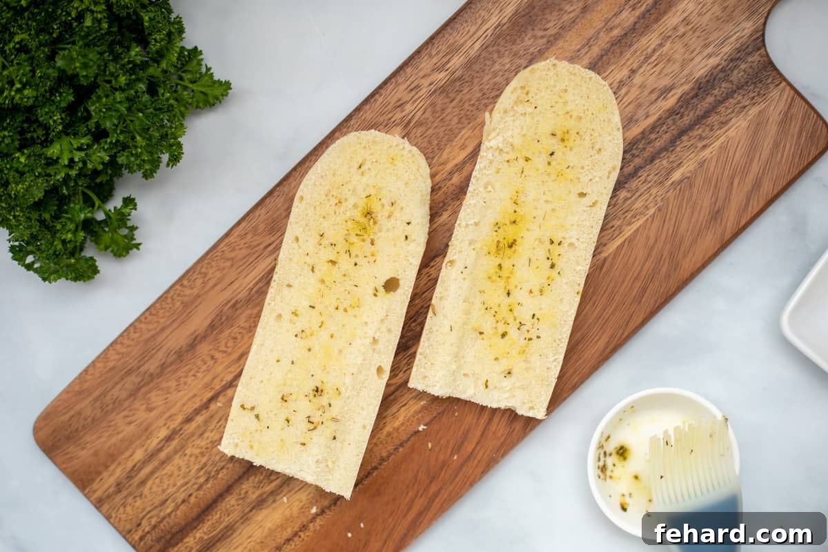 Sliced French bread pieces being brushed with a mixture of seasoned olive oil, preparing them for the air fryer to achieve a crispy crust.