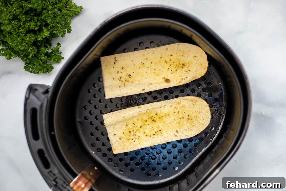 Lightly toasted French bread slices arranged inside an air fryer basket, demonstrating the initial crisping stage before adding any pizza toppings.