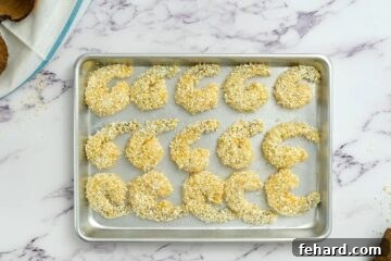 Breading shrimp with coconut and breadcrumbs on a baking sheet.
