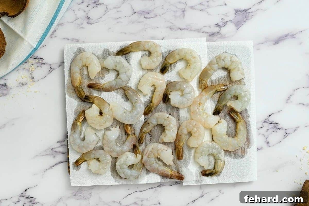 Raw shrimp being carefully patted dry with paper towels on a clean surface.