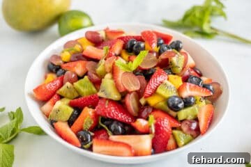 Fruit Salad in white serving dish topped with fresh mint.