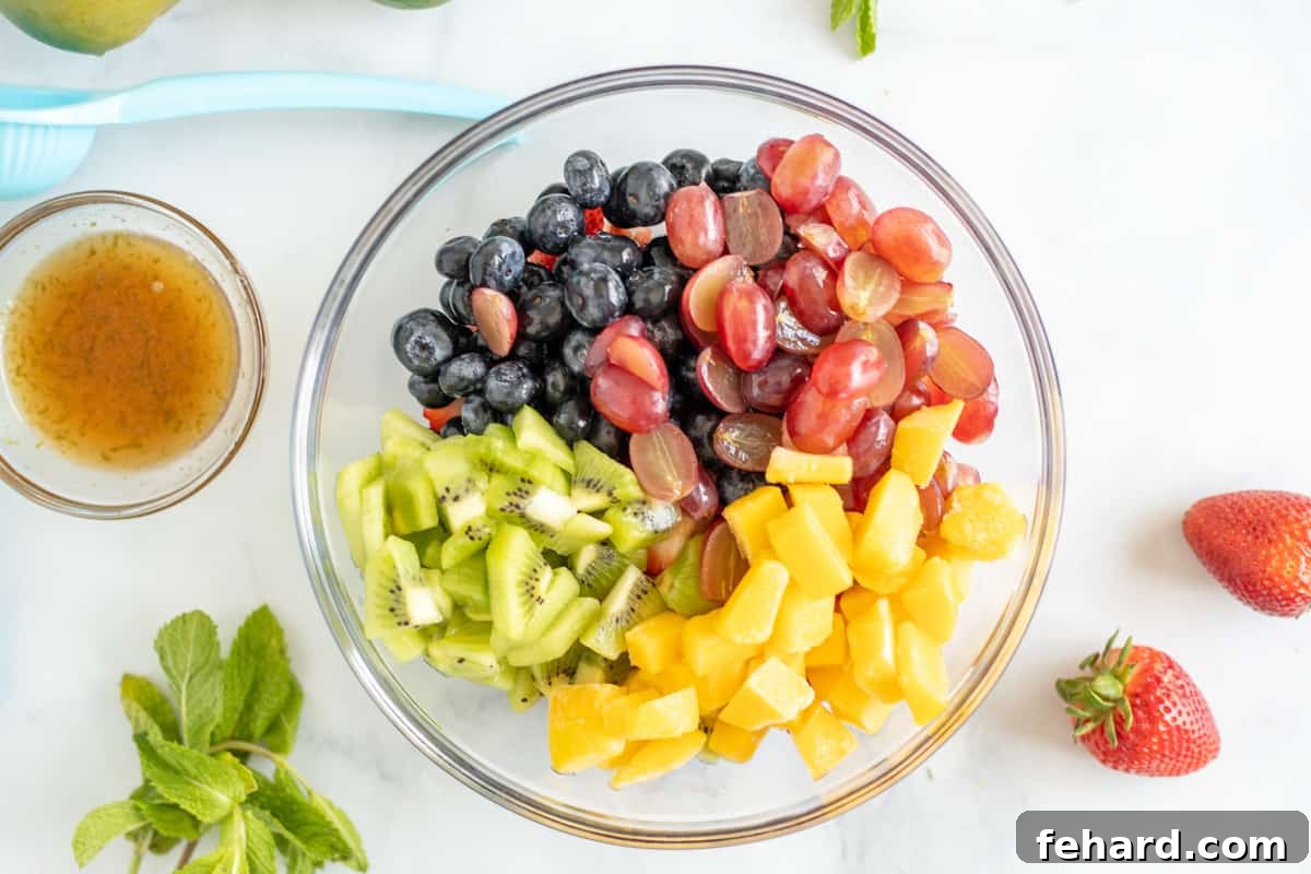 Recipe for Fresh Fruit Salad Preparation Kiwi, mango, grapes, blueberries, and strawberries in mixing bowl, ready to be combined.