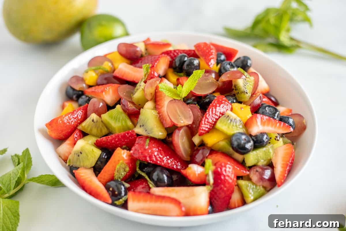 Fruit Salad with Honey Lime Dressing and Mint Garnish Fruit Salad with honey lime dressing in a white serving dish, garnished with fresh mint.