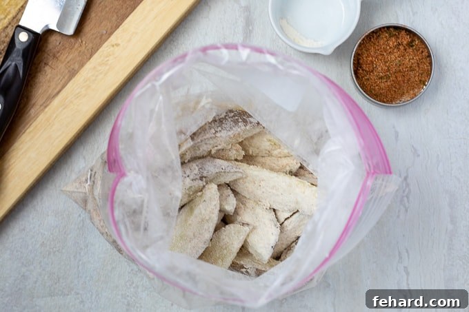 A resealable bag filled with potato wedges coated in seasoning, ready for baking.