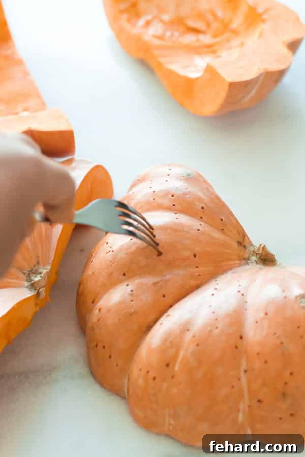 Pumpkin wedges placed flesh-side down on a foil-lined baking sheet, ready for the oven.