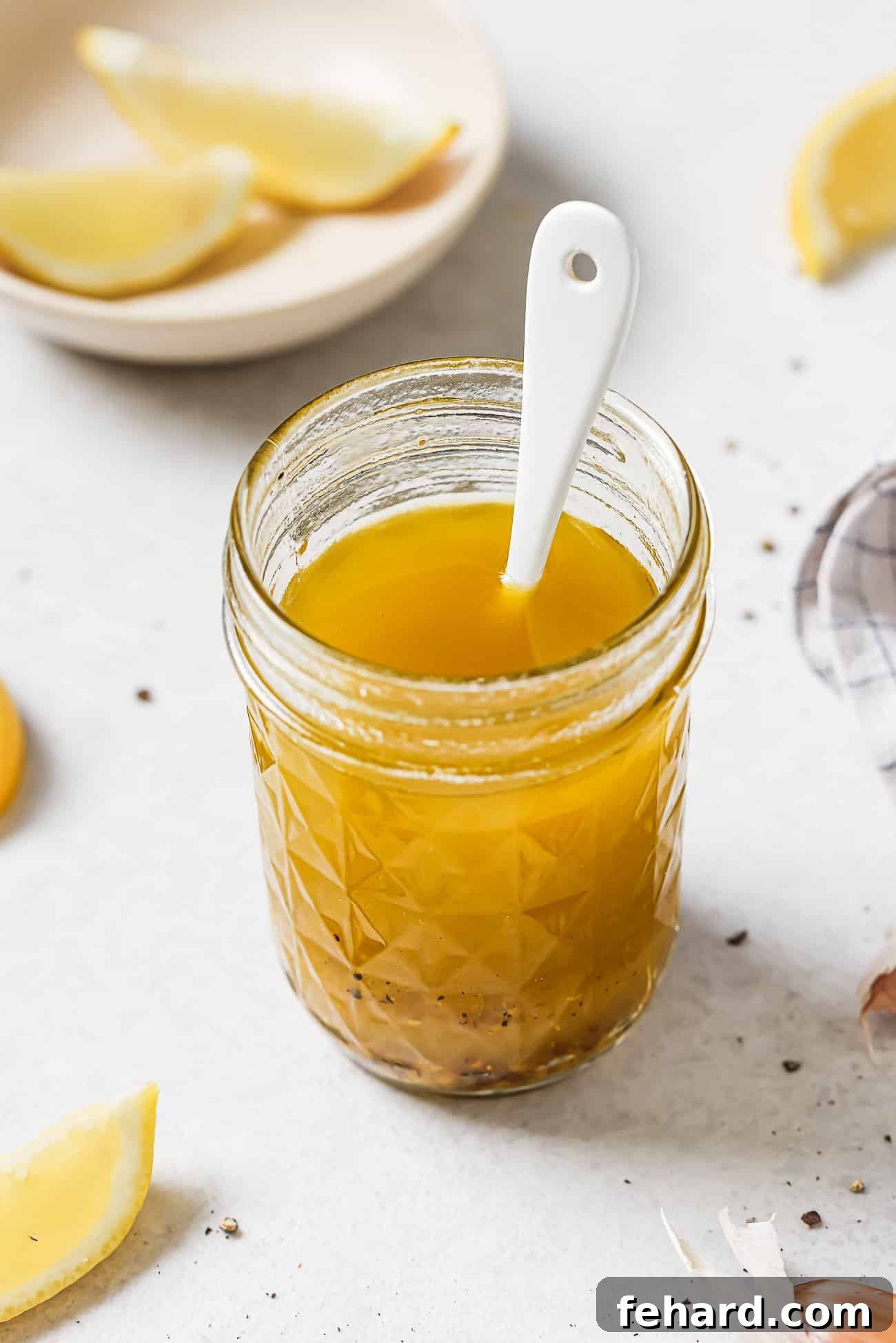 Vinaigrette dressing in a jar with a white spoon in it.