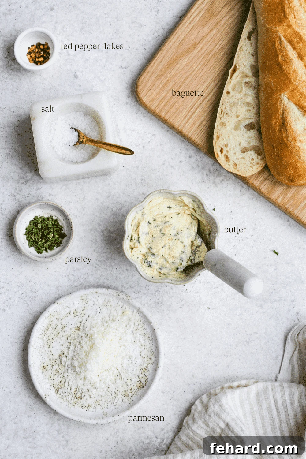 Ingredients for garlic bread arranged on a white countertop.