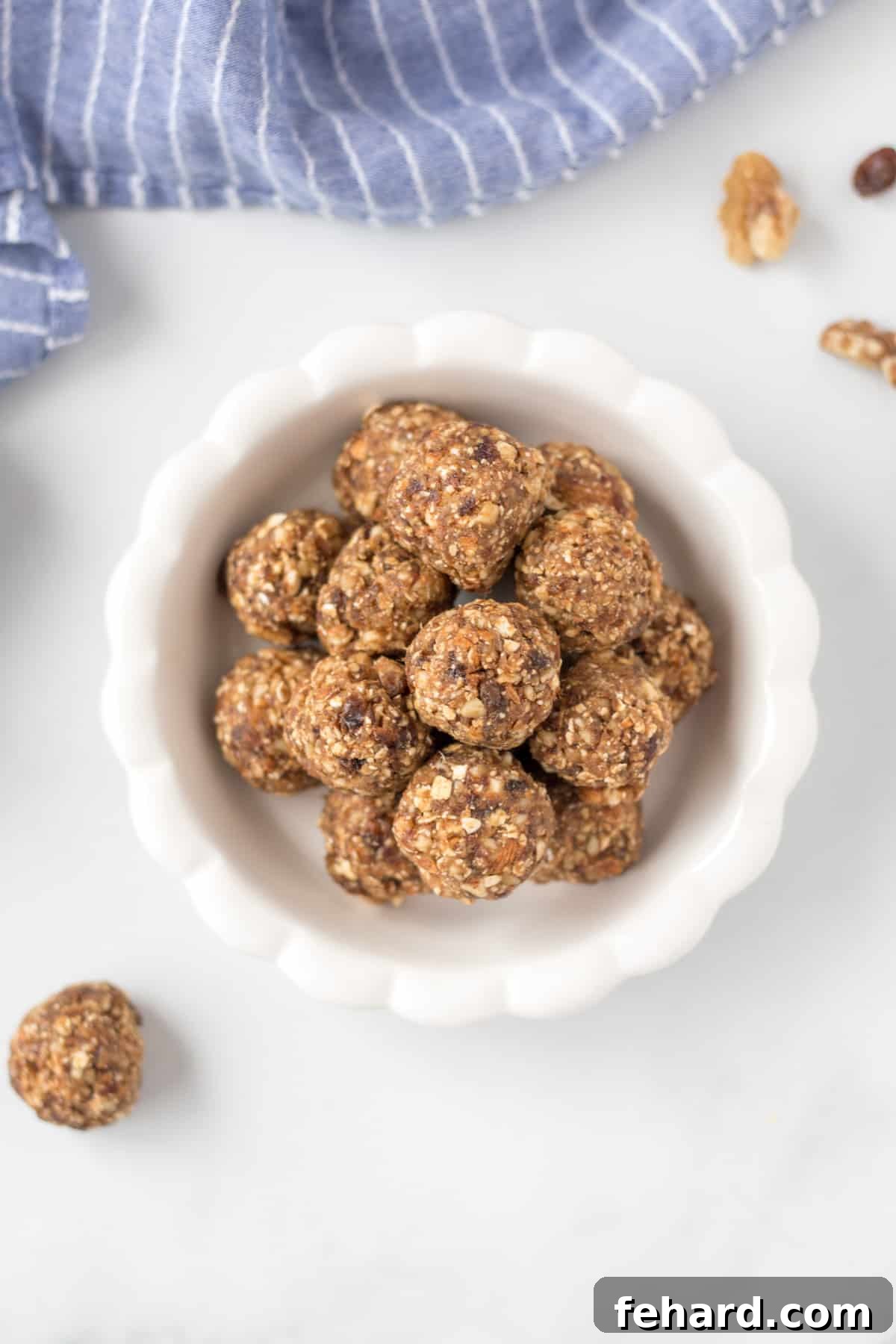 Best No Bake Energy Balls Recipe Stacked Oatmeal Energy Bites in a white bowl, accompanied by walnuts and dates, highlighting natural ingredients.
