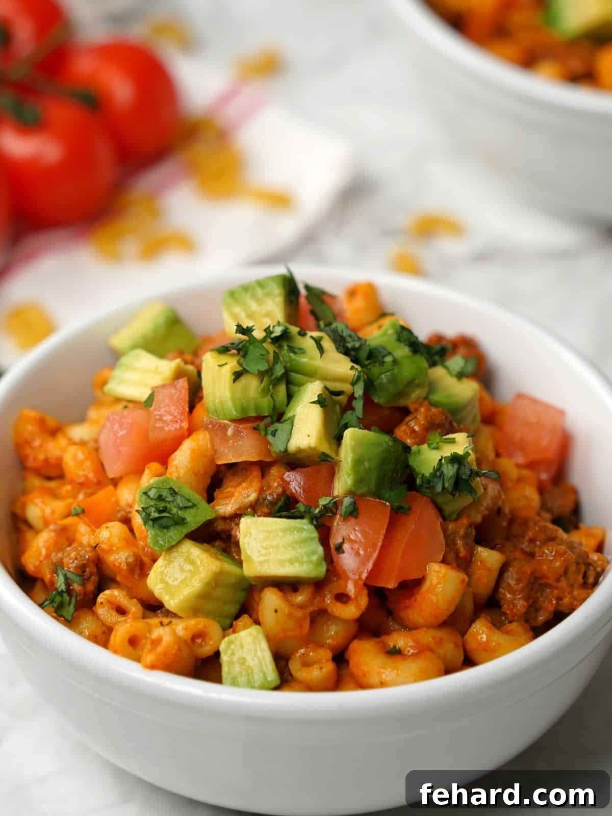 Instant Pot Taco Pasta - Cheesy & Quick Family Meal A vibrant bowl of Instant Pot Taco Pasta, generously topped with fresh diced avocado, juicy diced tomatoes, and a sprinkle of shredded cheese and cilantro, ready to be enjoyed.
